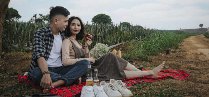 Man and woman sitting on red blanket having a picnic