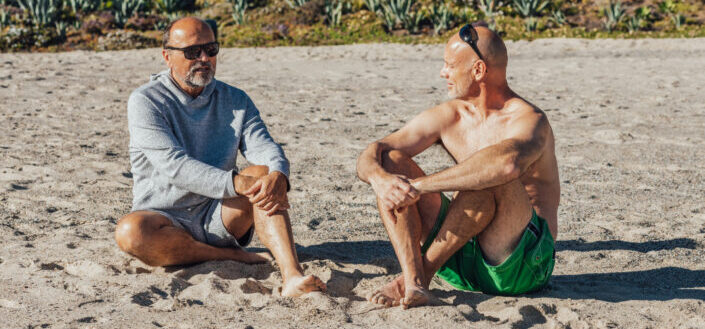 An Elderly Men Sitting on the Beach Sand while Having Conversation