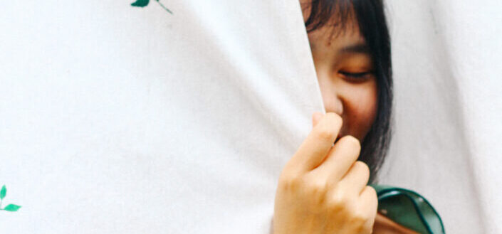 a woman hiding behind a big white cloth