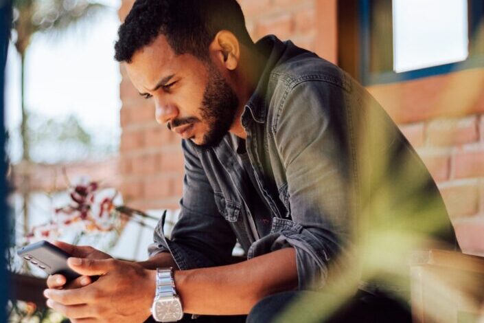 man in grey shirt using smartphone