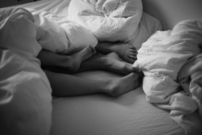 two people lying in a bed with only their feet visible