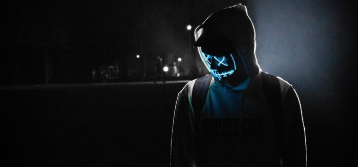 Man wearing a glowing mask and a hoodie