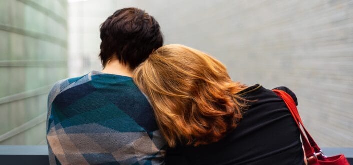 Blonde haired woman leaning on his guy's shoulders