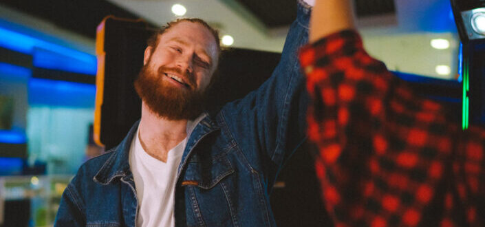 A Man in Denim Jacket Smiling while Doing High Five