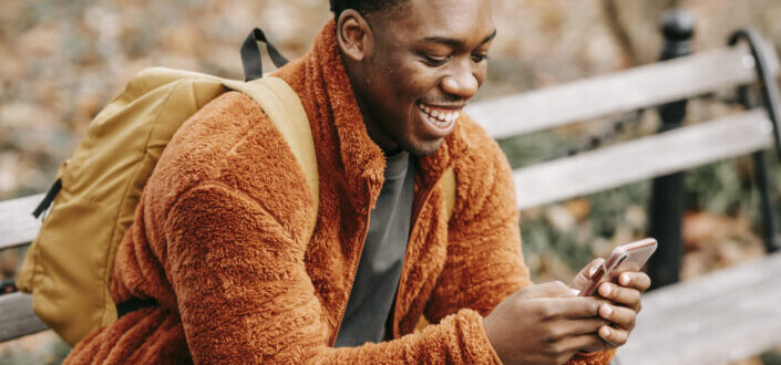 Happy Guy on a Park Bench With a Smartphone