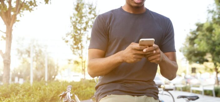 Man Holding Smartphone Outside During Daytime