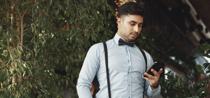 Man in Dress Shirt and Black Dress Pants Holding Black Smartphone