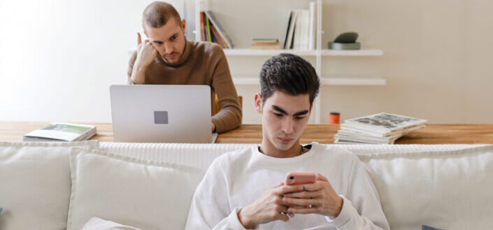 Man in Sweater Using Phone While Sitting on White Sofa