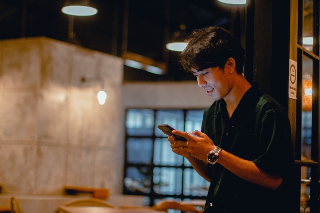 man smiling while texting - how to text your crush without being boring