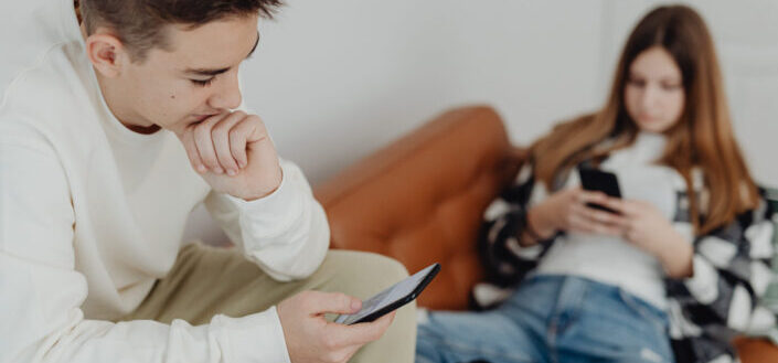 Boy and Girl Sitting on a Couch and Using Smartphones