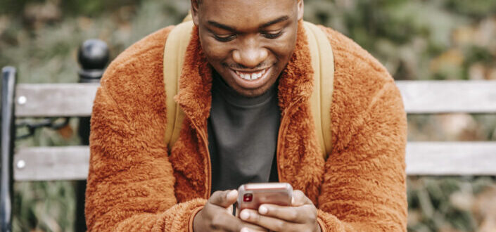 Man Smiling While on His Phone in City Park