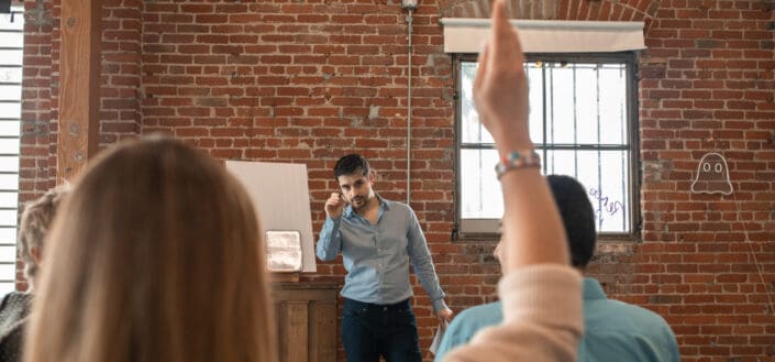 Teacher pointing the pen at the person raising hand