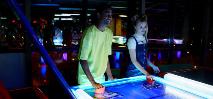 A couple playing table hockey in an arcade