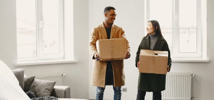 A couple standing while carrying boxes