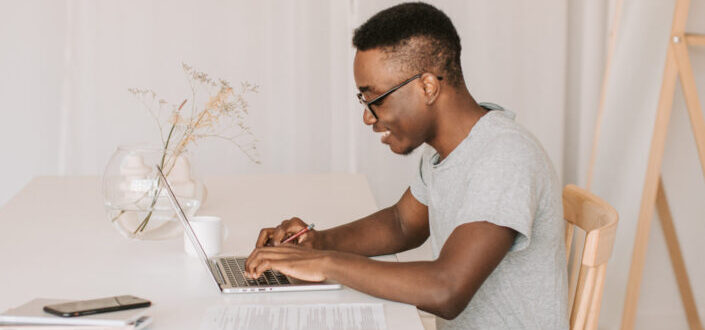 A man smiling while typing on a laptop