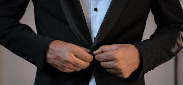 Businessman buttoning up blazer of elegant suit