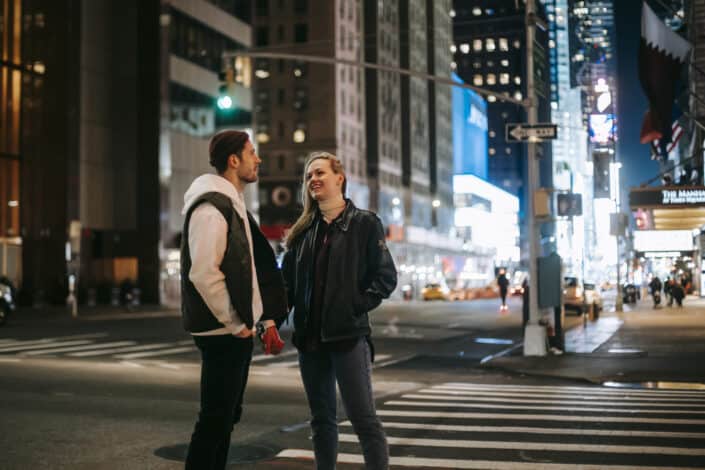 Cheerful couple standing on crosswalk at night time