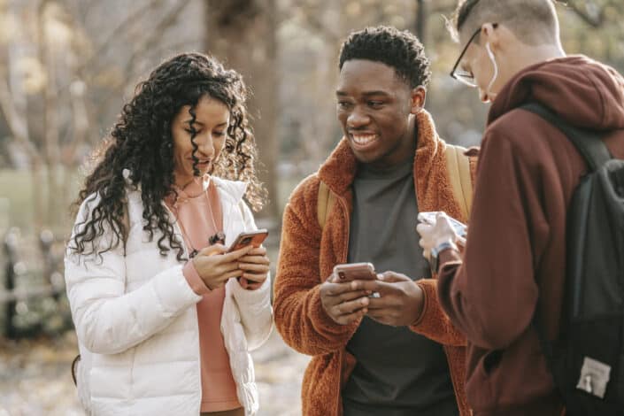 Friends with smartphones in park