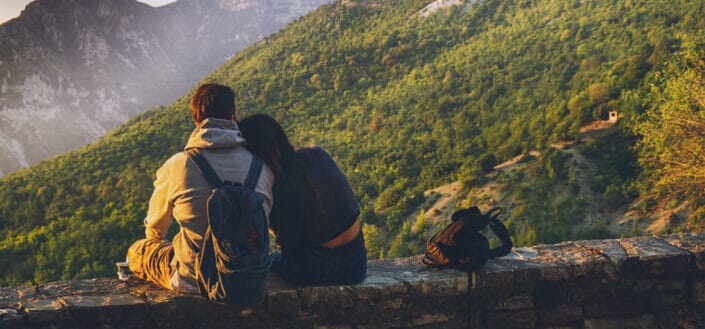 Couples sitting in while facing mountain