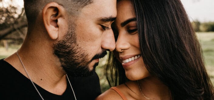 Crop hispanic couple touching noses in countryside field