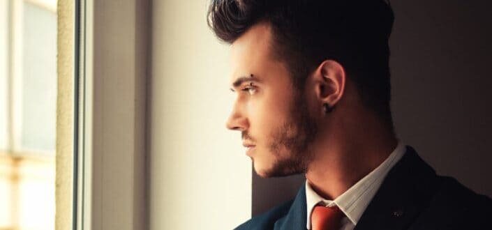 A guy with eyebrow piercing wearing formal attire staring at the window