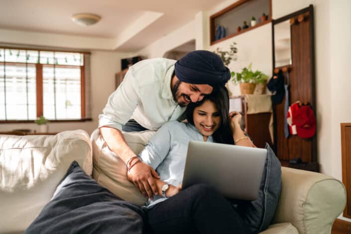 Happy couple using laptop at home together