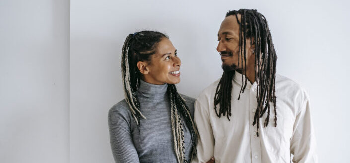Happy ethnic couple with braids standing close
