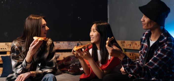 Happy friends hanging out together and eating pizza