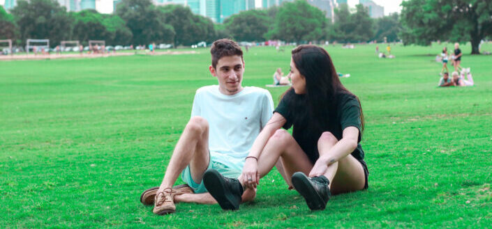 Happy young couple resting on lawn in park