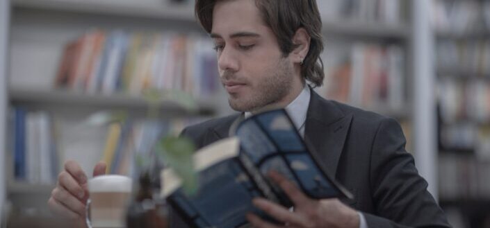 a man drinking coffee while reading a book