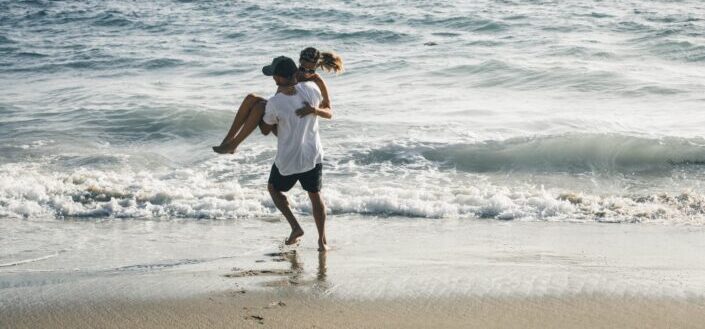 Man carrying a woman on the beach