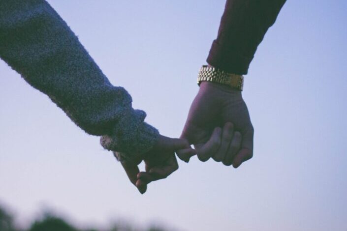 man and woman holding hand using pinky fingers