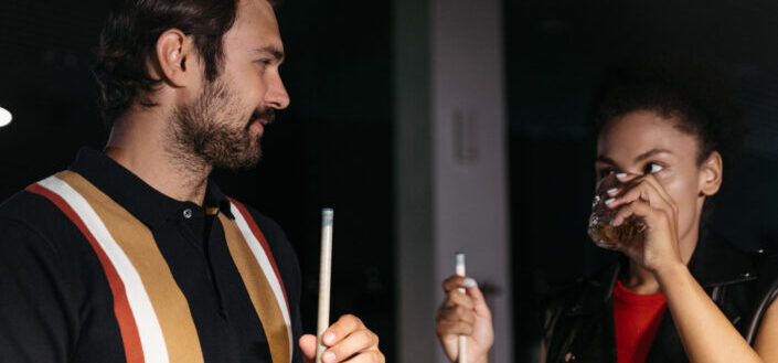 Couple looking at each other while holding cue sticks