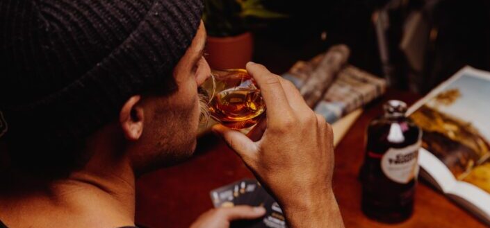 man in black knit cap holding clear glass mug