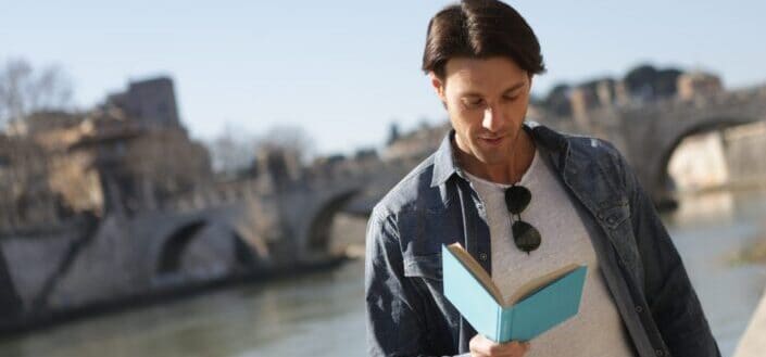 Man in blue denim jacket reading a book