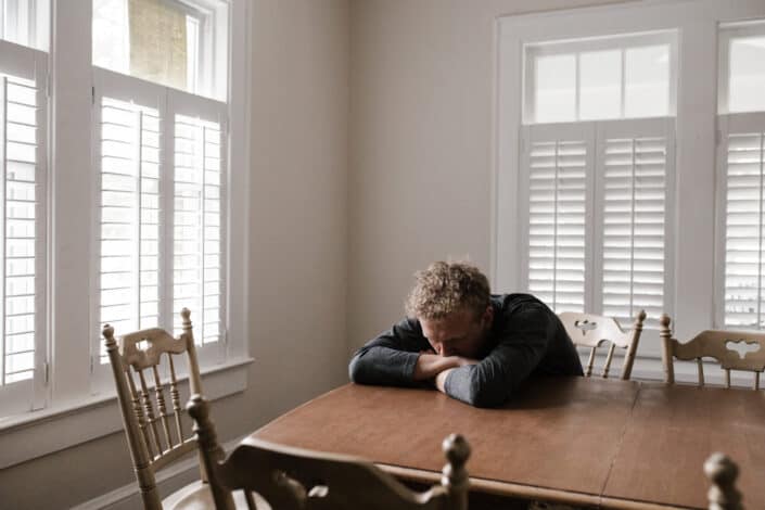 Man in gray long sleeve shirt sitting on brown wooden chair