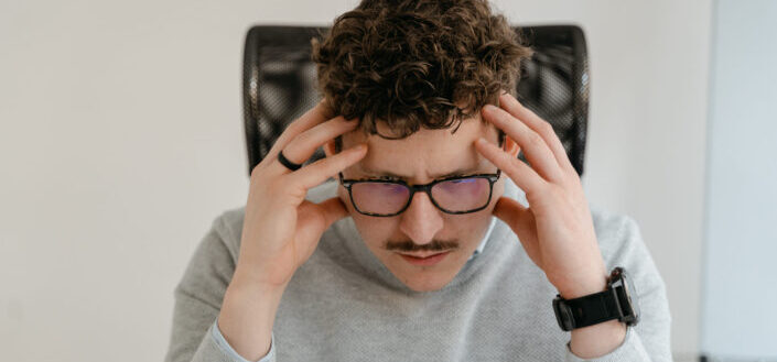 Confused man in gray sweater holding his head with hands