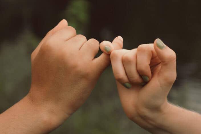 Two people making a pinky promise