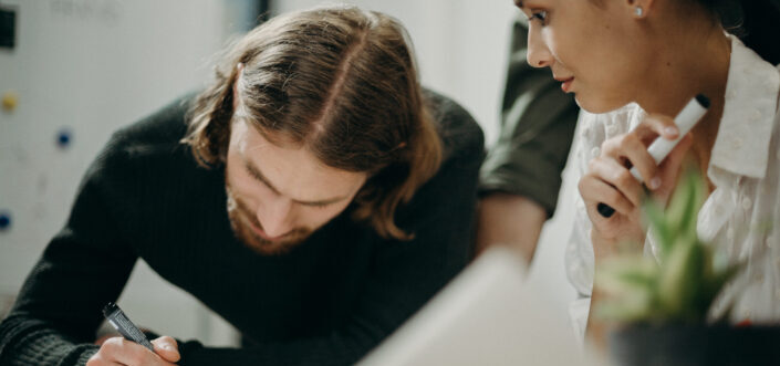 Man writing on paper beside woman