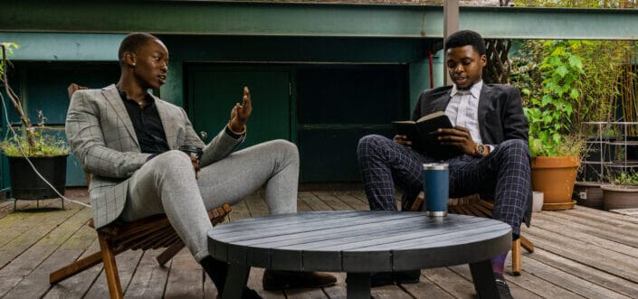 Men sitting on a wooden chair while having conversation