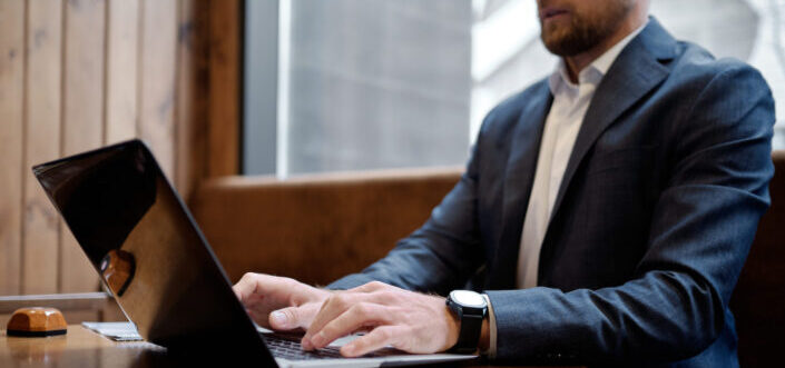 man in blue suit jacket using a laptop