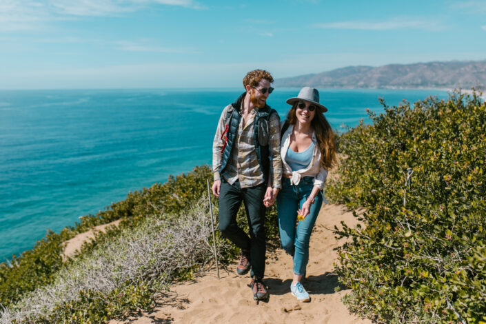 Photograph of a couple holding hands near the sea