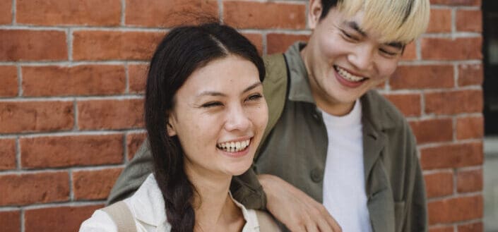 Happy couple standing near brick wall