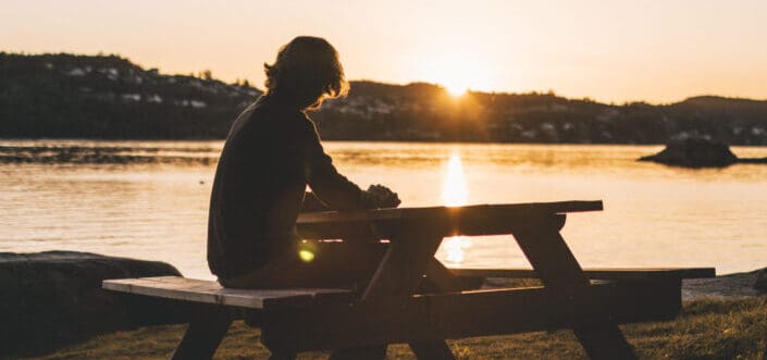 Silhouette of person sitting on picnic table