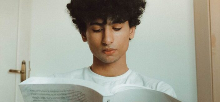 A curly man reading a book