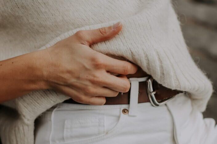 a woman wearing a white outfit with brown belt