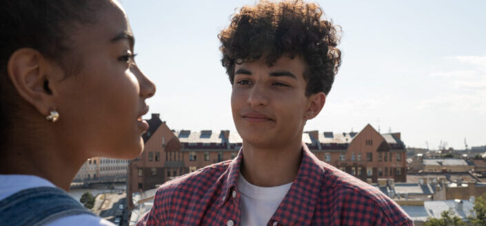 Teenagers standing on rooftop talking and looking at each other