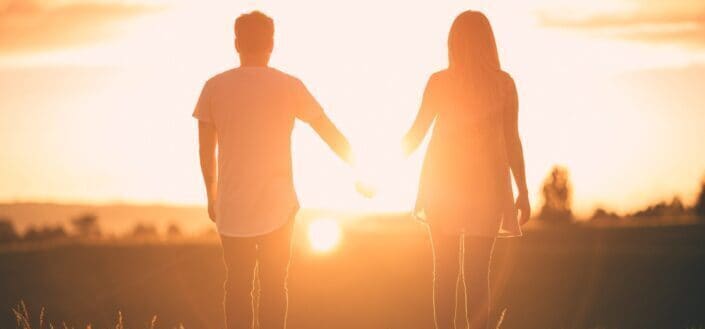 couple holding hands while watching sunset together