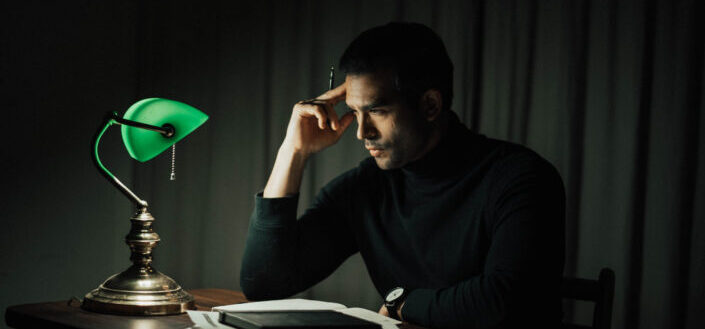 Wistful man with documents at table in dark room