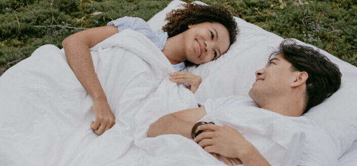 A couple lying down on a mattress outdoors